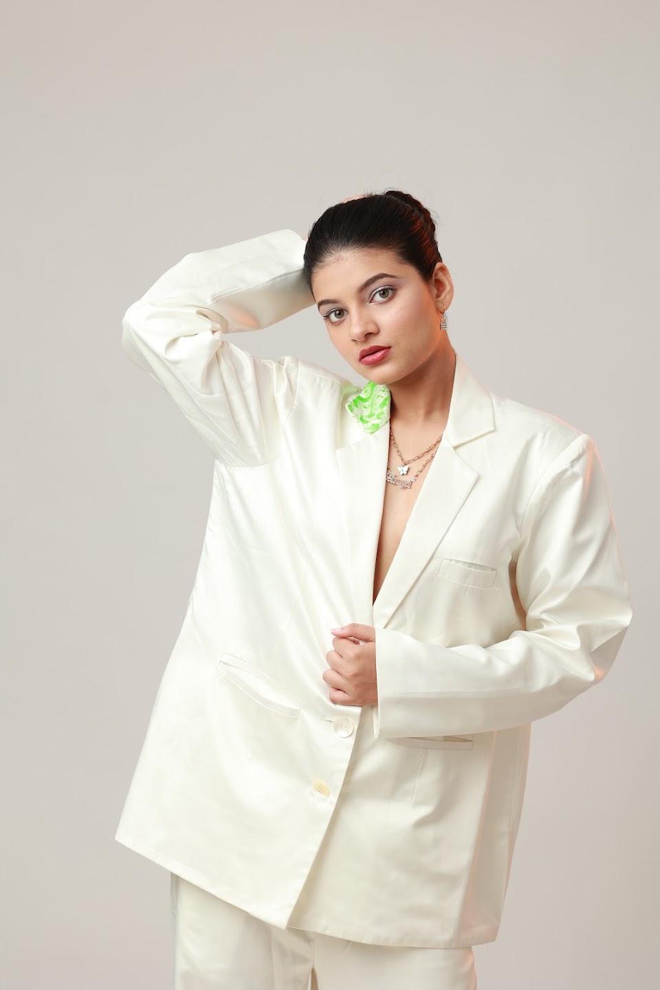Editorial portrait in a white suit with a vivid green earring