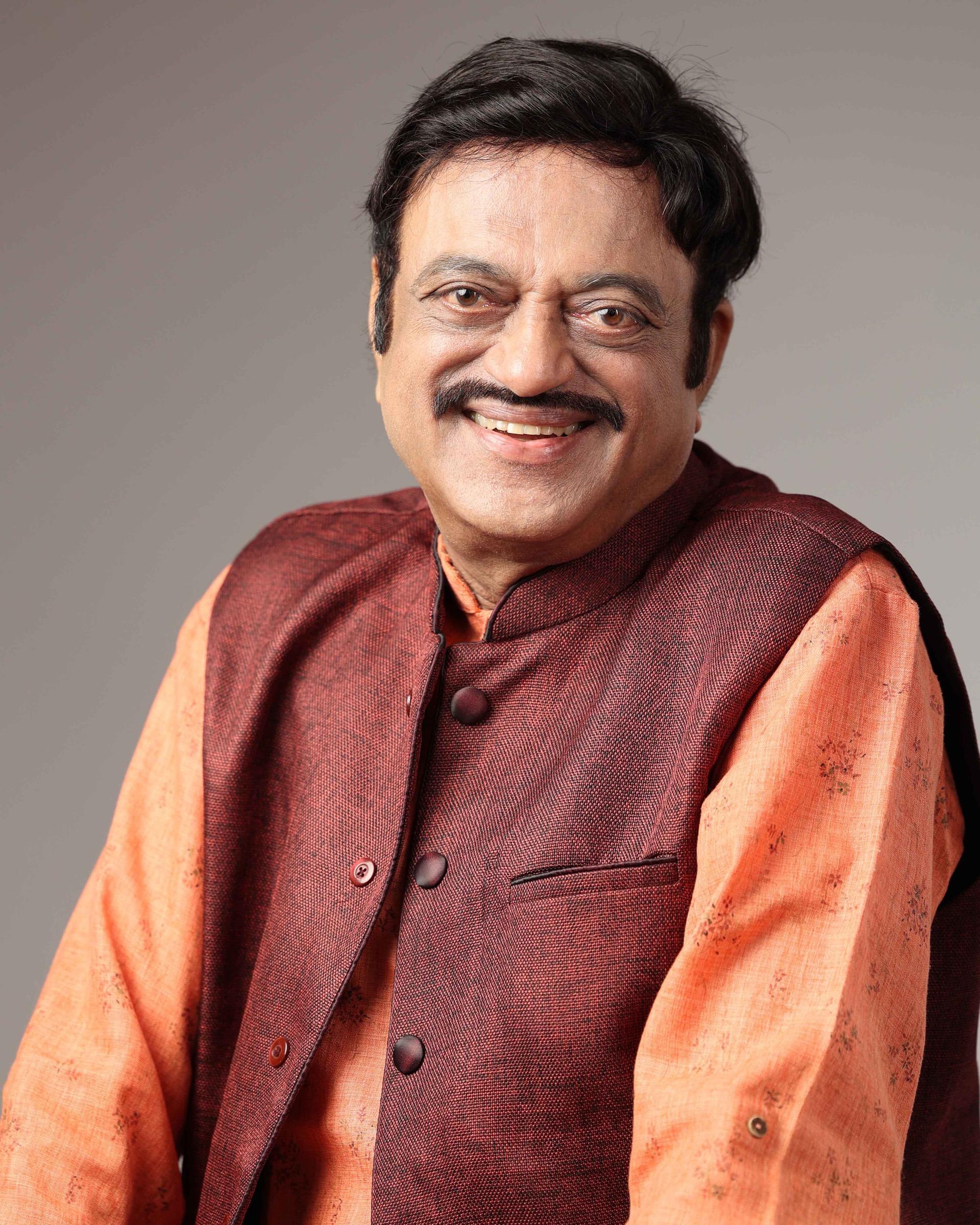 Warm professional portrait of a smiling man in a maroon waistcoat